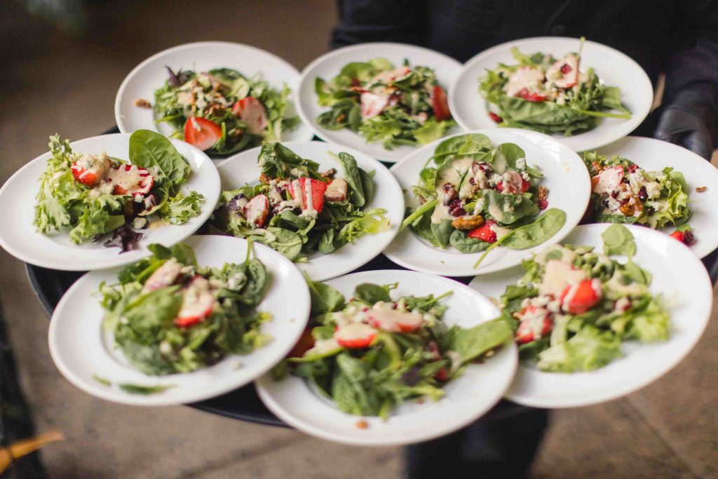At a wedding, a person showcases the intricate details by skillfully holding plates of salads on a tray.