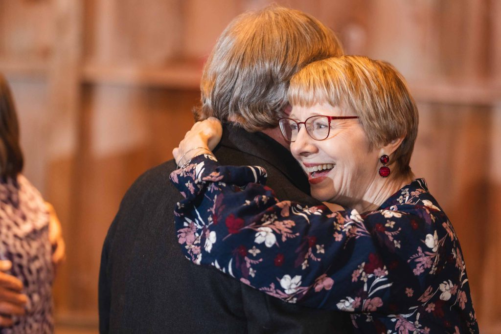 An older woman is hugging another woman at a wedding reception.