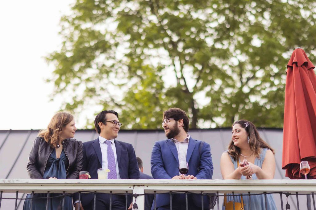 A candid group of people standing on a balcony during wedding preparation.