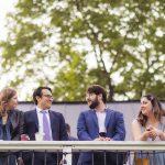A candid group of people standing on a balcony during wedding preparation.