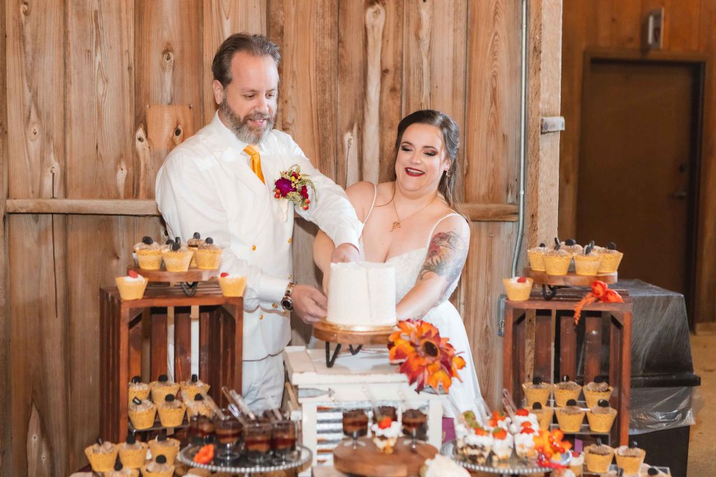 A couple cutting their wedding cake at their reception in a barn.