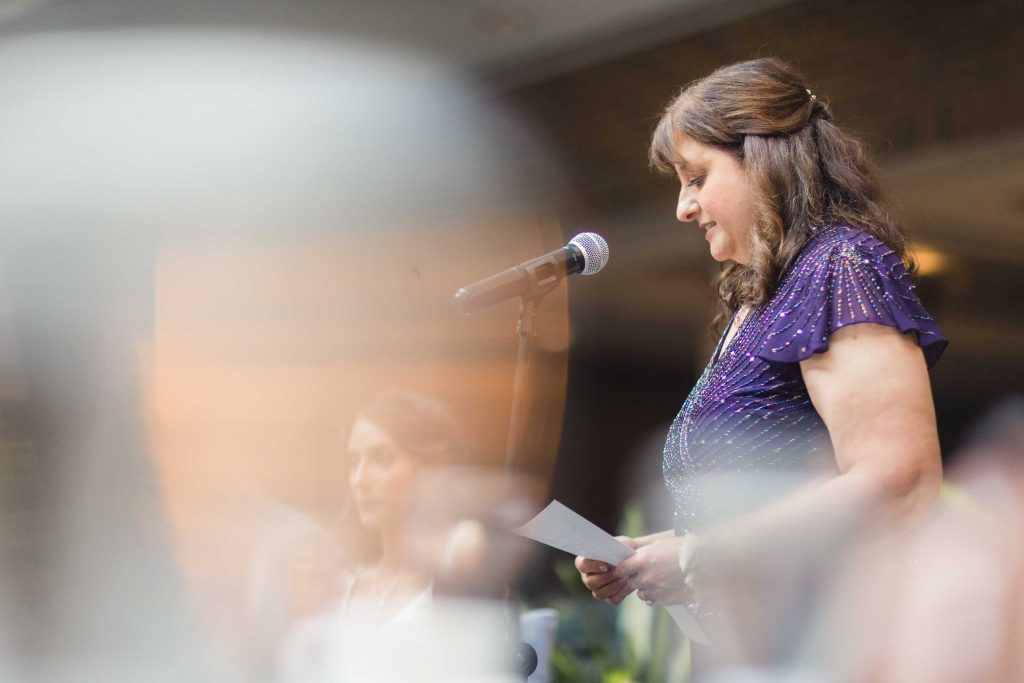A woman speaking into a microphone at a wedding reception.
