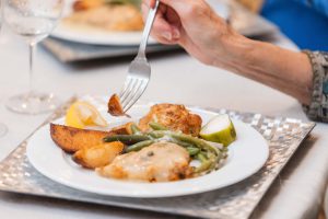 A woman is holding a fork and eating with attention to details.