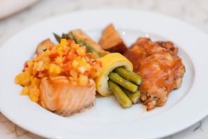 A white plate with salmon, asparagus and other food at a wedding.