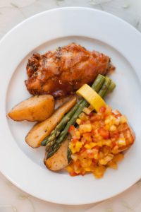 A white plate with chicken and asparagus, elegantly displayed.