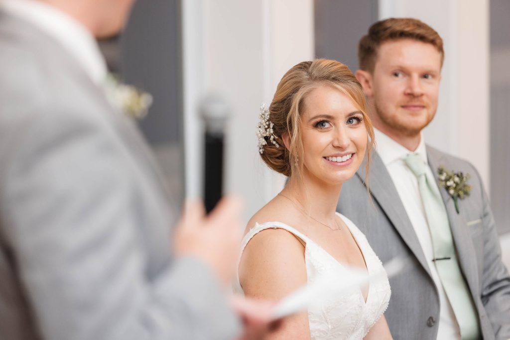 A bride and groom smiling at each other during their wedding ceremony.