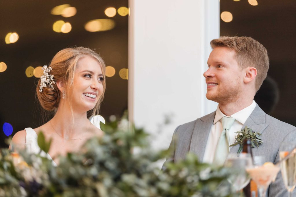 A couple smiling at each other during their wedding reception.