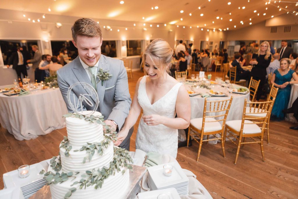 A bride and groom cutting their wedding cake at the reception.