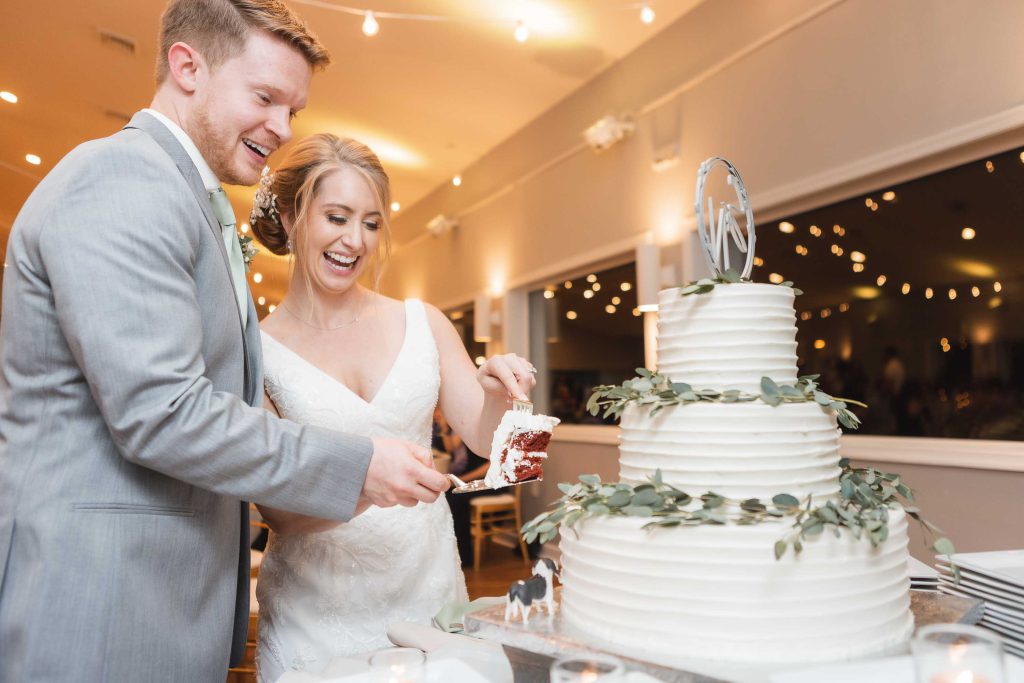 A bride and groom enjoying their wedding reception, cutting into their beautiful wedding cake.