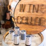A wooden sign with the words "wine cellar" on it sits on top of a wooden barrel at a birthday party.