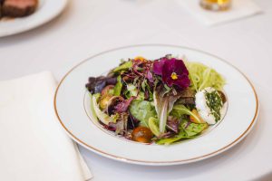 A white plate with a salad on it, perfect for wedding details.