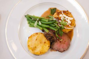 A plate with steak, potatoes, and green beans at a wedding reception.