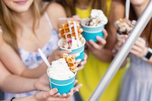 A group of girls celebrating a birthday party with cups of ice cream.