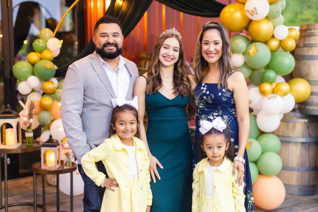 A family posing in front of balloons at a baby shower.