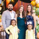 A family posing in front of balloons at a baby shower.
