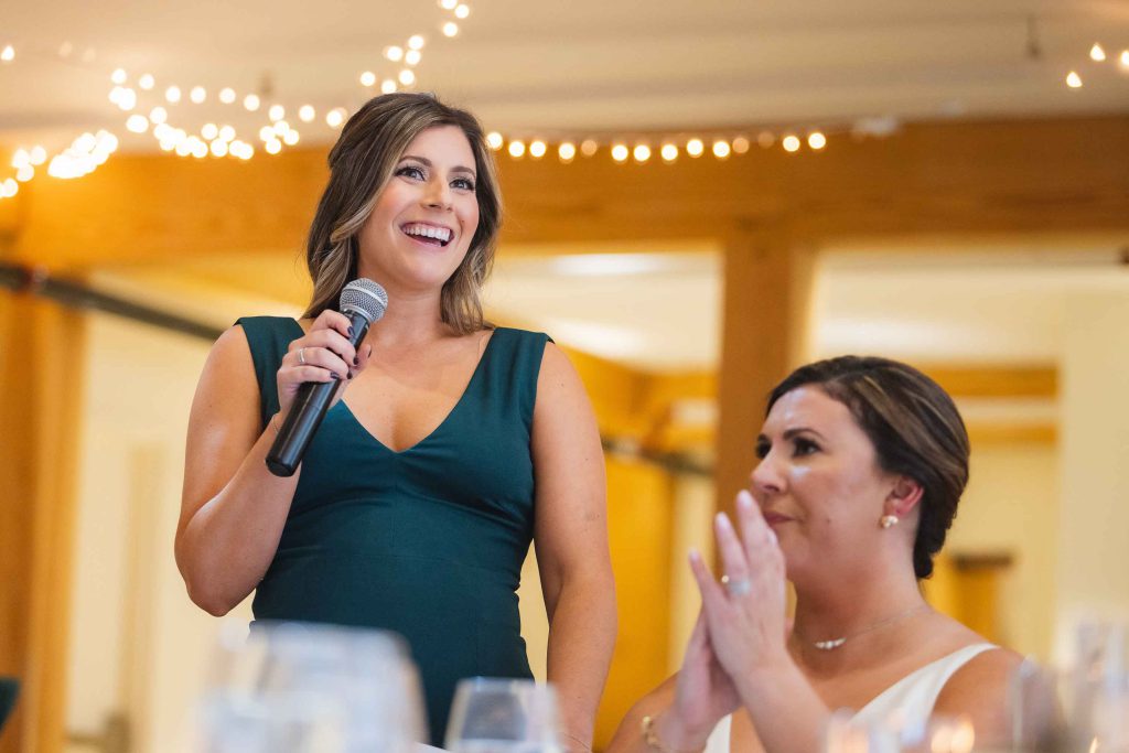 A woman is speaking into a microphone at a wedding reception.