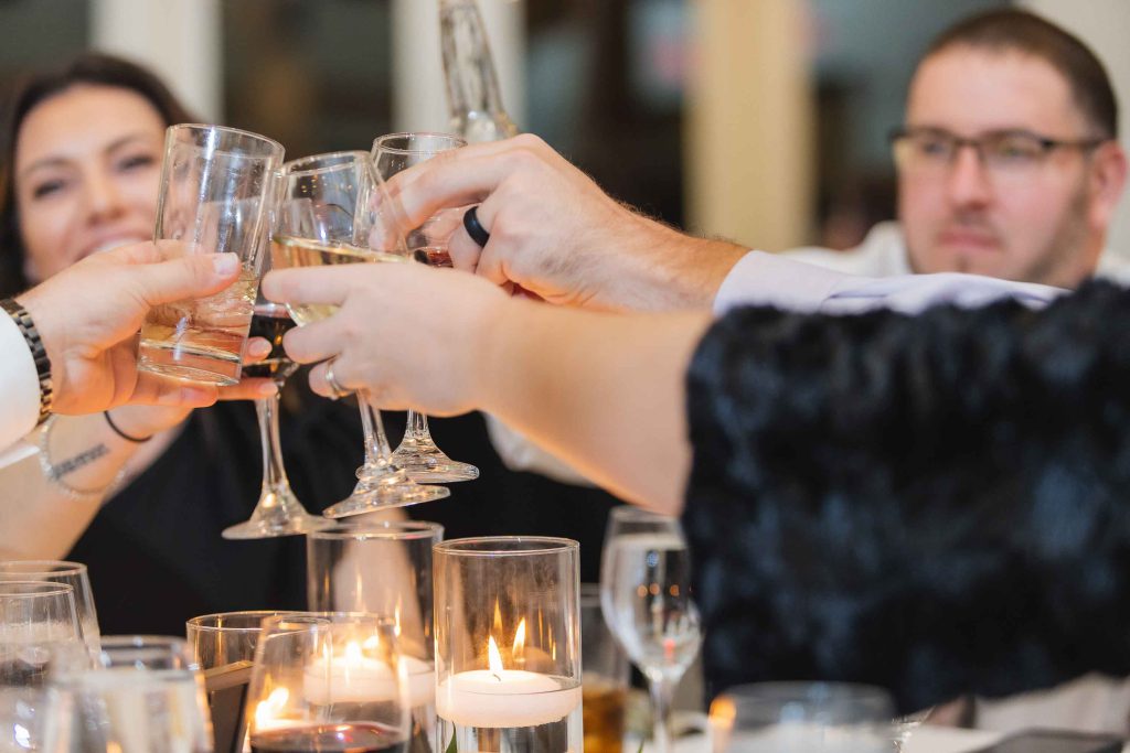 A group of people toasting wine glasses at a wedding reception dinner party.