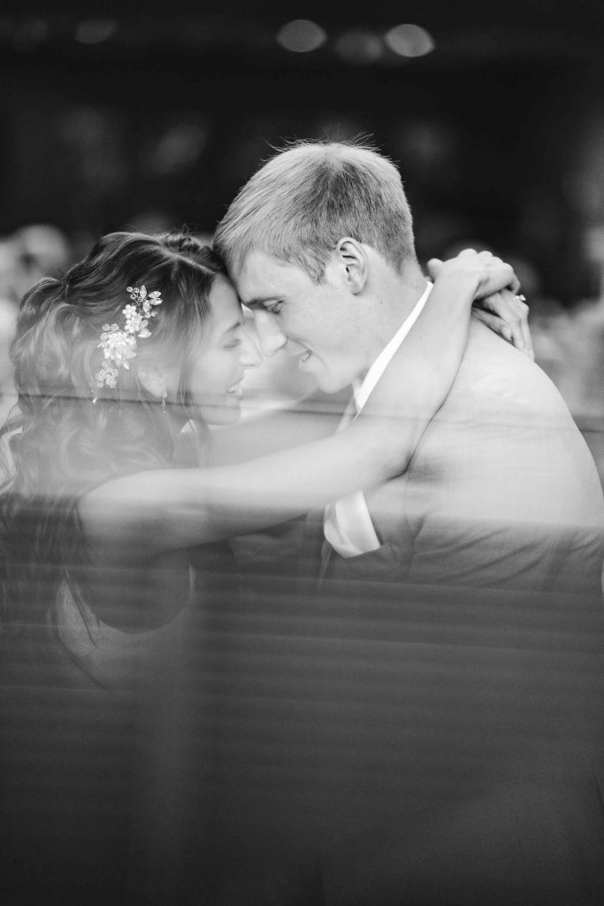 A black and white photo of a bride and groom hugging during their wedding.