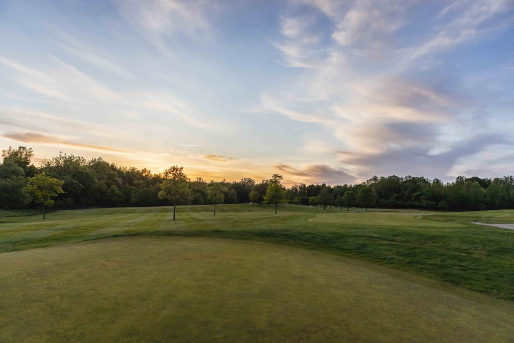 An aerial view of a golf course at sunset with wedding details.