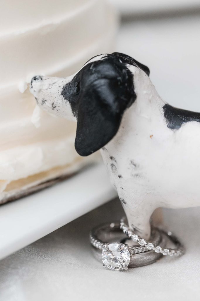 A wedding cake topper featuring a dachshund with a ring.