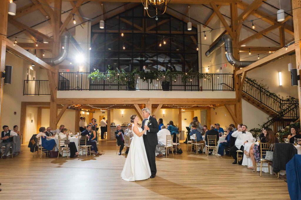A bride and groom's first dance during their wedding reception in a barn.