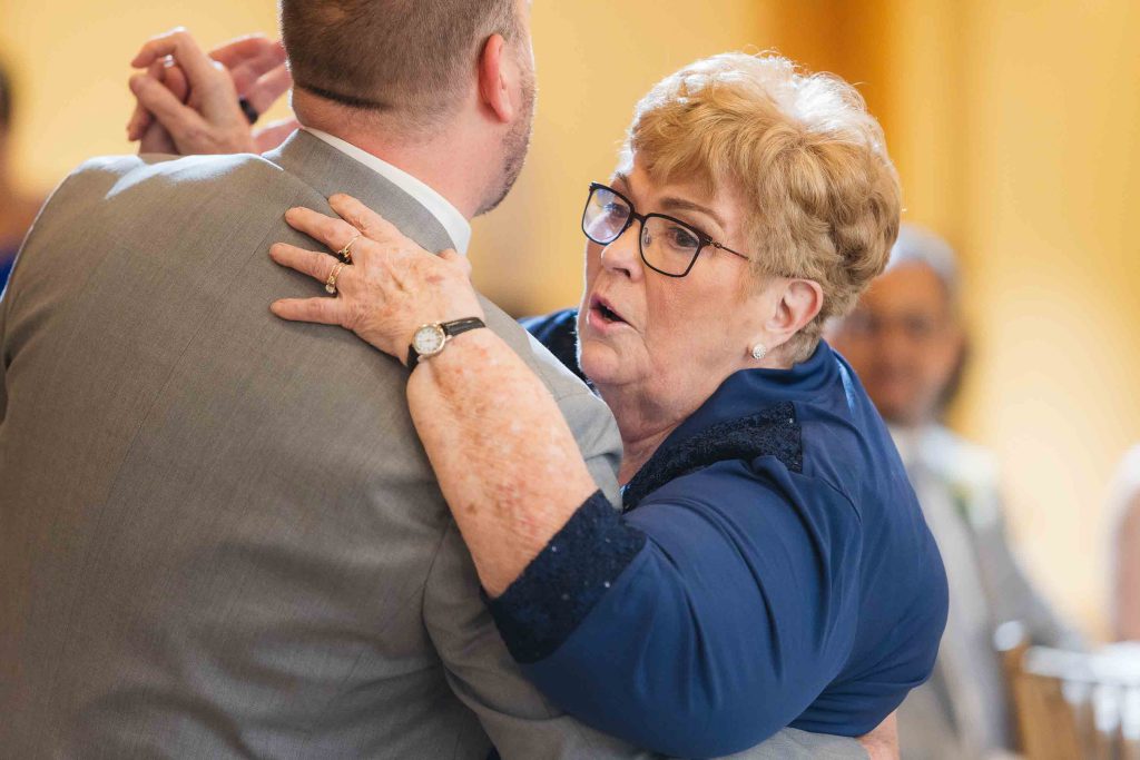 A woman is hugging an older man at a wedding reception.