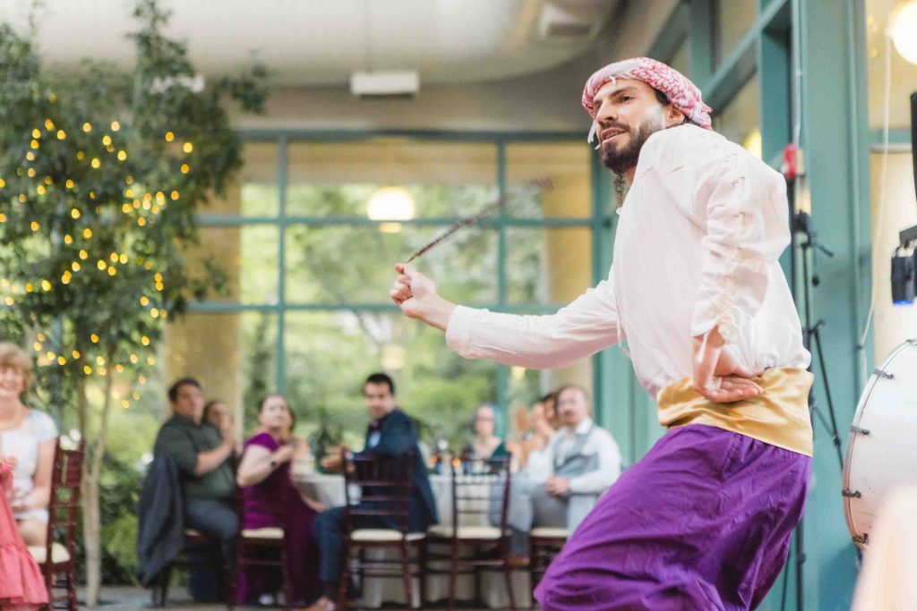 A man in a purple dress dancing at a wedding reception.