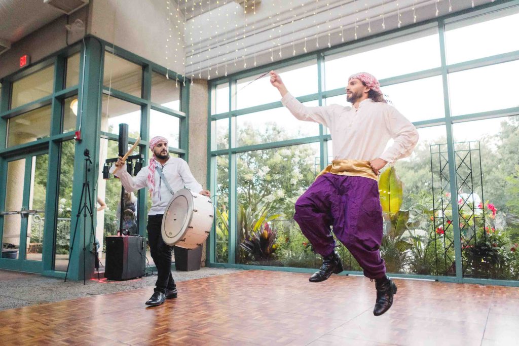 Two men are dancing at a wedding reception.