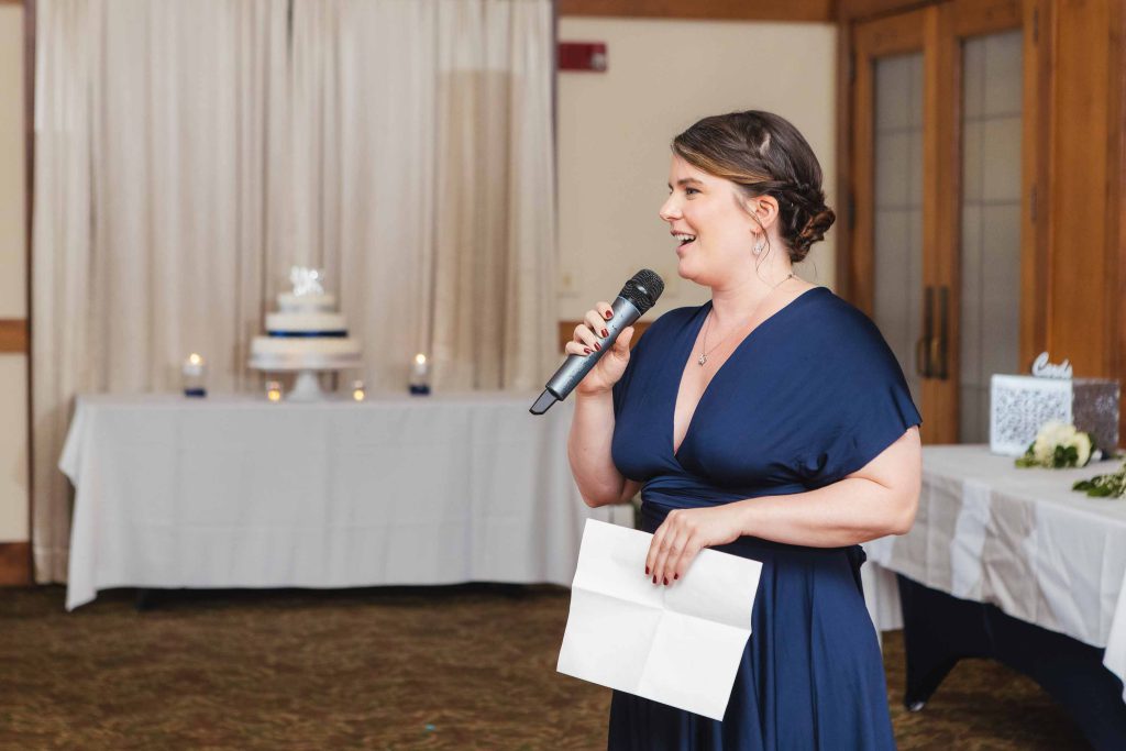 A woman speaking into a microphone at a wedding reception.