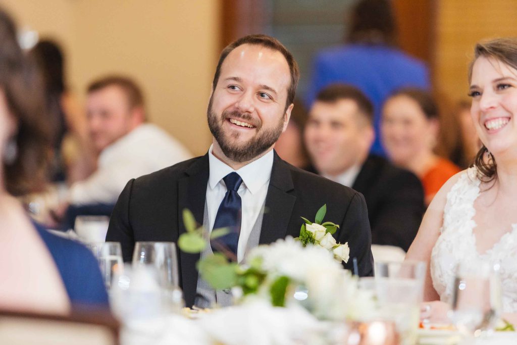 A couple smiling at each other during a wedding reception.