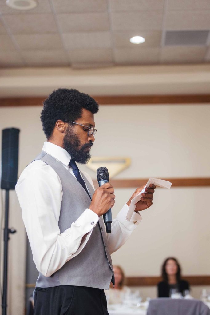 A man speaking at a wedding reception.