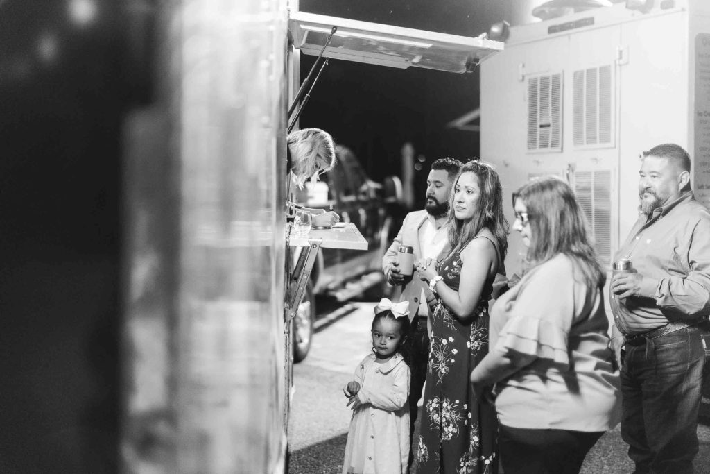 A group of people standing in front of a food truck at a birthday party or quinceañera celebration.