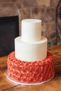 A wedding cake adorned with red roses.