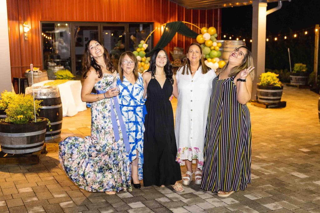 A group of women posing for a photo at a Birthday Party in front of wine barrels.