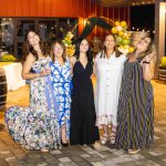 A group of women posing for a photo at a Birthday Party in front of wine barrels.