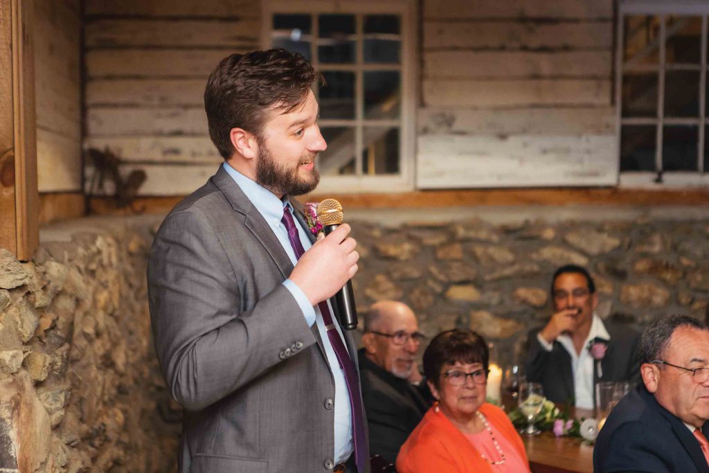 A man speaking into a microphone at a wedding reception.