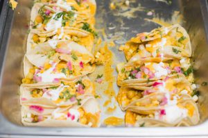 A tray of wedding tacos with sour cream and onions.