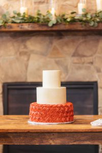 A wedding cake with intricate details displayed on a rustic wooden table.