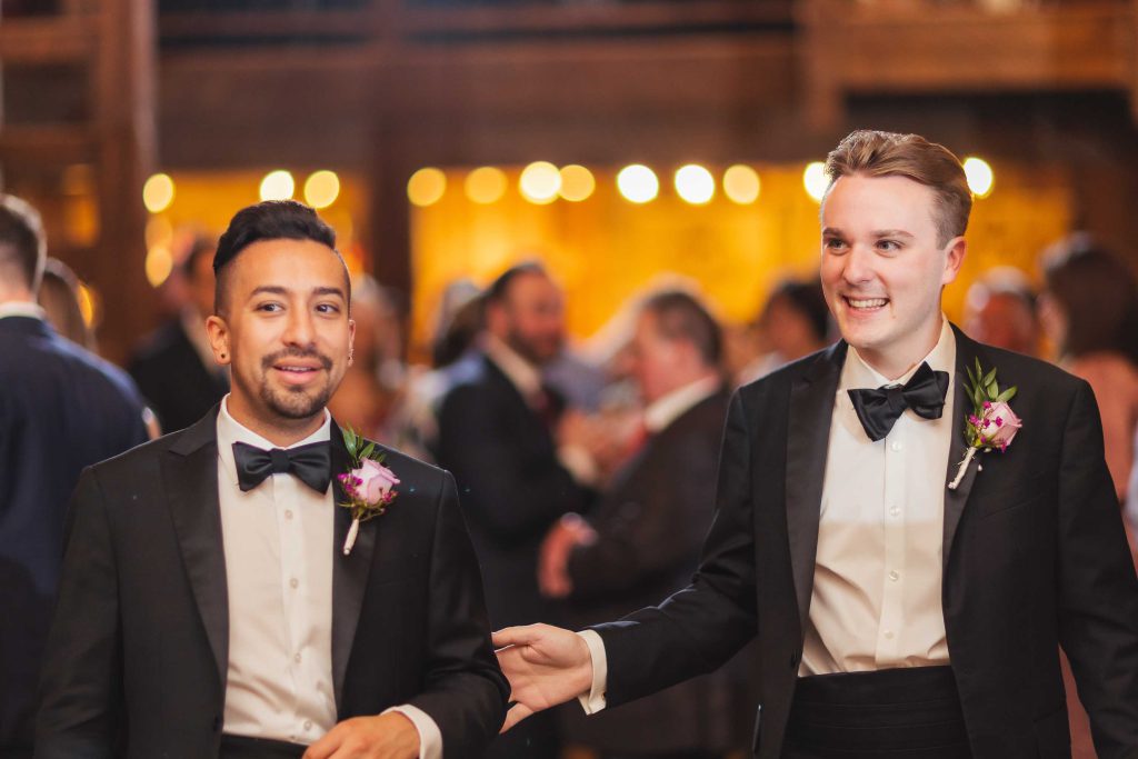 Two men in tuxedos walking down the wedding aisle.