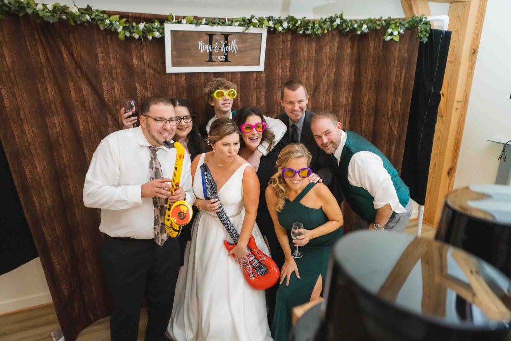 A group of people posing for a photo at a wedding reception in a photo booth.