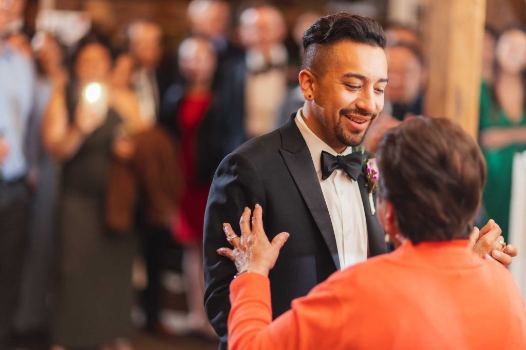 A man in a tuxedo is dancing with his mother at a wedding reception.