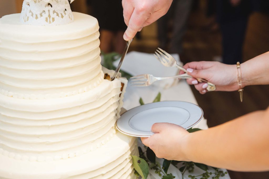 A person cutting a wedding cake at the reception.