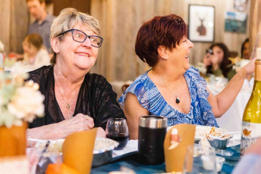 A group of women laughing at a dinner table during a Birthday Party gathering.