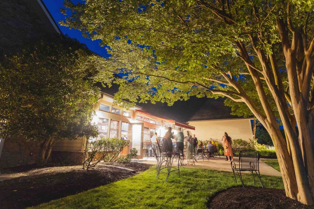 A group of people standing in a yard at night for a wedding.