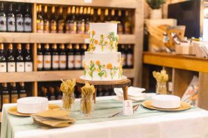 A wedding cake with sunflowers on it sits on a table.