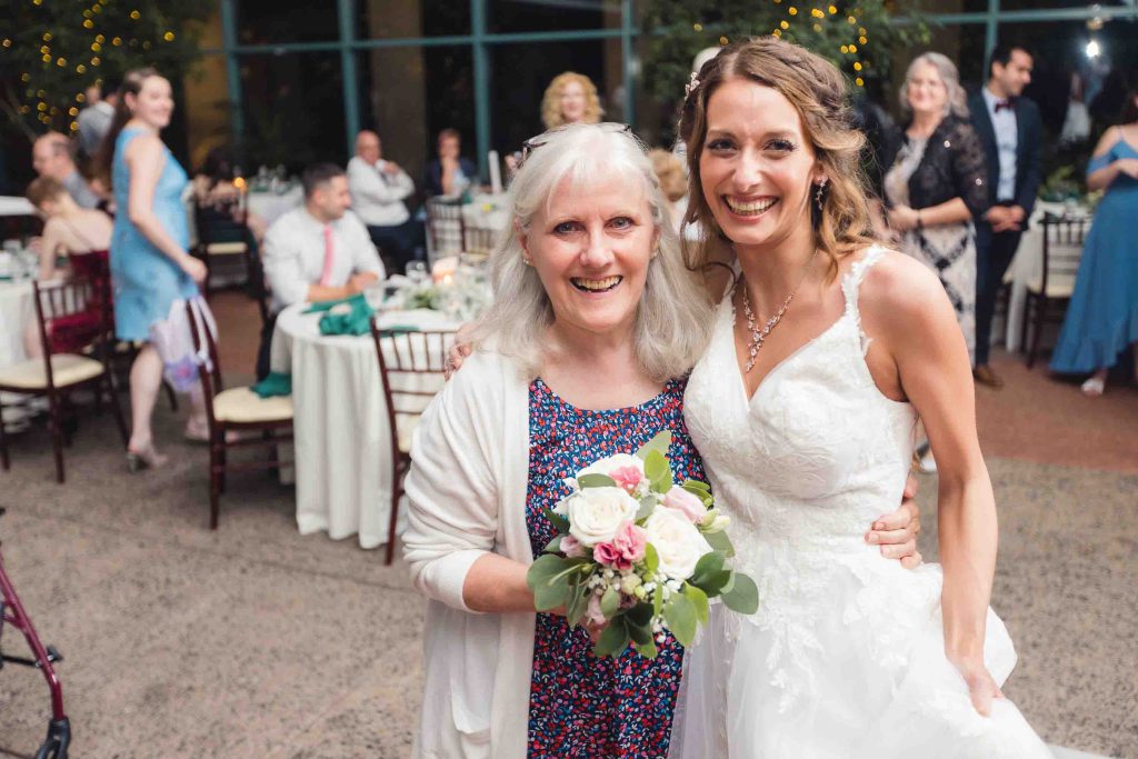 A bride and her mother posing for a photo at a wedding reception.