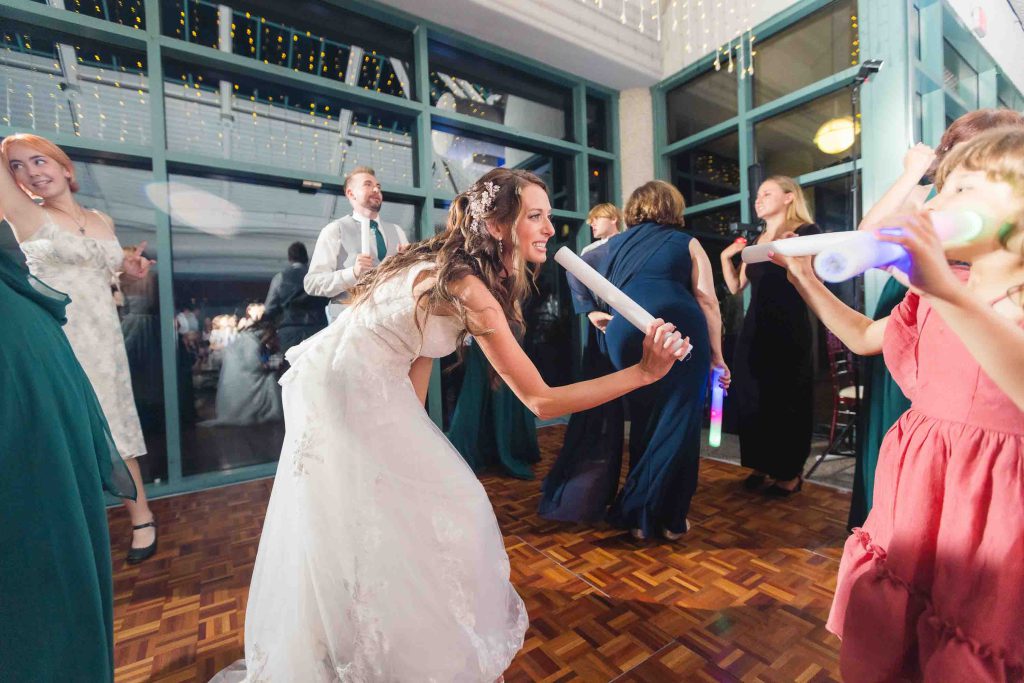 A bride and her bridesmaids having a fun lightsaber battle at the wedding reception.