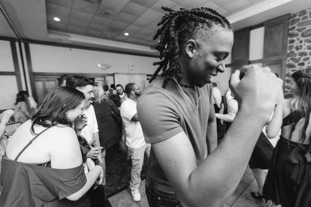A black and white photo of a man dancing at a wedding reception.