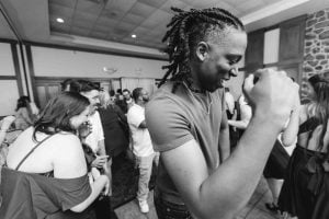 A black and white photo of a man dancing at a wedding reception.