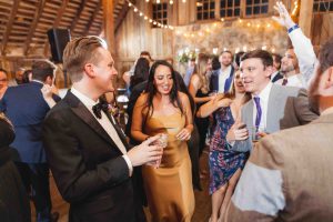 A group of people dancing at a wedding reception in a barn.